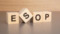 four wooden cubes with the letters ESOP on the bright surface of a brown table, business concept