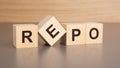 four wooden cubes with the letters REPO on the bright surface of a brown table, business concept