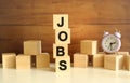 Four wooden cubes stacked vertically on a brown background form the word JOBS.