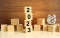 Four wooden cubes stacked vertically on a brown background form the word 2023.