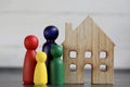 Wooden figures family standing in front of a wooden house.