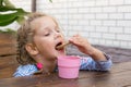 Four-year girl eating waffles and drinking tea at a table on the veranda