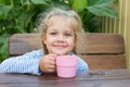 Four-year girl smiling while sitting at a table with a glass of juice