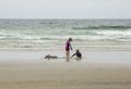 Two young children, a boy and a girl, playing in the sand and water at the beach Royalty Free Stock Photo