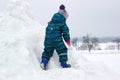 A four-year-old child, a boy, is climbing a snowy hill