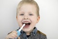 Four year old child brushes his teeth with an electric brush. The boy on a white background laughs and holds a toothbrush. The