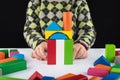 Four year old girl plays in the designer on the table. Wooden toys, colorful children`s designer, black background, entertainment Royalty Free Stock Photo