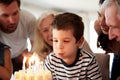 Four year old white boy celebrating with family blowing out candles on his birthday cake, close up Royalty Free Stock Photo