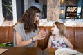 Little girl laughing with mother sitting in restaurant Royalty Free Stock Photo