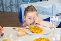 Funny little girl eating paella and looking at you