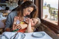 little girl laughing embraced in arms of mother sitting in restaurant Royalty Free Stock Photo