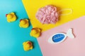 Four yellow rubber ducks, shower sponge and thermometer for water on a blue, pink and yellow background. Bath concept. Copy space Royalty Free Stock Photo