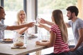 Four young adult friends laughing and raising glasses to make a toast during a dinner party, close up Royalty Free Stock Photo
