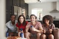 Four young adult friends watching sports on TV at home Royalty Free Stock Photo