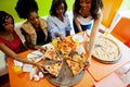 Four young african girls in bright colored restaurant eating pizza Royalty Free Stock Photo