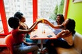 Four young african girls cheers with orange juices while sitting in bright colored fast food restaurant