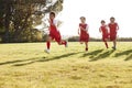 Four young boys in football strip running in a playing field