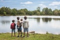 Four young brothers contemplating a large pond on a day trip