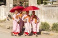 Four young Burmese nuns in pink, orange and red robes walking