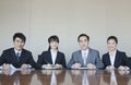 Four Young business people sitting in a row at a conference table, portrait Royalty Free Stock Photo