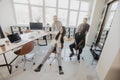 Unstoppable team. Four young cheerful business people in smart casual wear having fun while racing on office chairs and smiling Royalty Free Stock Photo