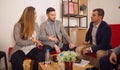 Four young entrepreneurs talking in a pleasant office spot while smiling and feeling relaxed