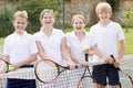 Four young friends on tennis court smiling