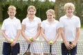 Four young friends on tennis court smiling