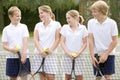 Four young friends on tennis court smiling