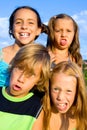 Four young kids making funny faces