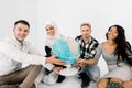 Four young multiracial people holding hands and hug Earth globe, sitting on the floor, on the white background. Save the Royalty Free Stock Photo