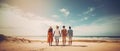 Four young people shot from behind standing hand in hand close to the sea beach, watching the beautiful seascape. Royalty Free Stock Photo