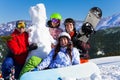 Four young people with snowboard and snowman Royalty Free Stock Photo