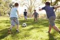 Four young schoolboys playing football together in the park