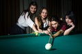 Four young women have fun with playing billiard