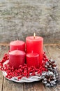 Four candles in a white wreath with red berries on a wooden rustic background. advent calendar for Christmas Royalty Free Stock Photo