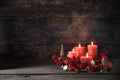 Fourth advent with lighted red candles in a wreath of decoration berries, Christmas balls and cinnamon star cookies against a dark Royalty Free Stock Photo