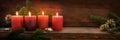 Fourth  Sunday in Advent, four burning red candles in a row, fir branches and Christmas decoration on dark rustic wood, wide Royalty Free Stock Photo