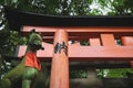 Fox kisune statue in front of orange torii gate in forest at the Fushimi Inari Taisha shrine in Kyoto, Japan Royalty Free Stock Photo