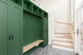 A foyer with a black and white pattern tile floor and green entryway bench.