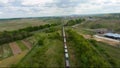 FPV drone flies quickly and maneuverable above a moving freight train. Automobile road on the background