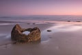 Fraction of a boulder on the ocean shore at sunrise