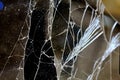Close-up view of broken glass with intricate cracks and patterns illuminated by soft light in a dimly lit room Royalty Free Stock Photo