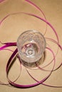 A small crystal glass on a stem with a crimson ribbon of serpentine on a background of craft paper.