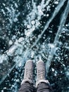 Fragile thin brittle ice underfoot. Female feet on ice. Woman wearing winter shoes