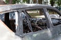 Fragment of an abandoned car damaged by fire. Vehicle has no windows and completely burnt-out interior. Side view, selective focus Royalty Free Stock Photo