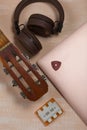 Fragment of acoustic guitar and notebook. Nearby are wireless headphones, a tuning fork and a pick. Against a background painted Royalty Free Stock Photo