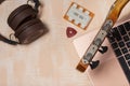 Fragment of acoustic guitar and notebook. Nearby are wireless headphones, a tuning fork and a pick. Against a background painted Royalty Free Stock Photo