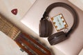 Fragment of acoustic guitar and notebook. Nearby are wireless headphones, a tuning fork and a pick. Against a background painted Royalty Free Stock Photo