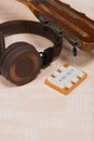 Fragment of acoustic guitar and tuning fork. Nearby are wireless headphones. Against a background painted in white and beige Royalty Free Stock Photo